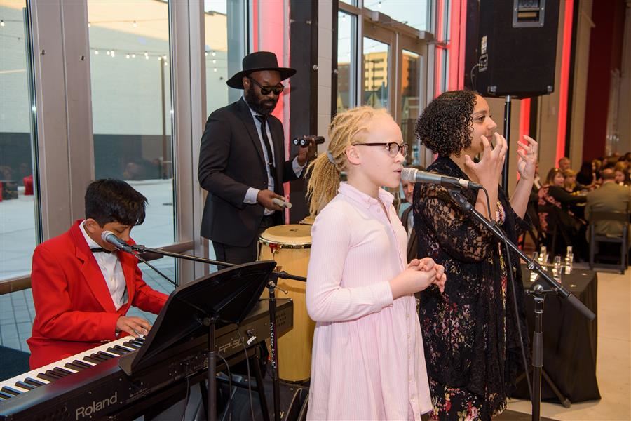  Students play the piano, sing, and sign while accompanied by Dave Crenshaw on drums.